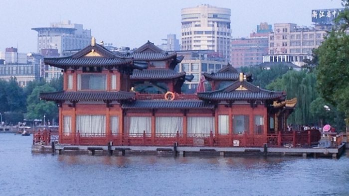 The Harmony of West Lake Hangzhou paviliun dengan latar belakang gedung tinggi