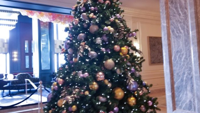 Pajangan pohon natal dengan bola warna-warni di tengah lobi hotel