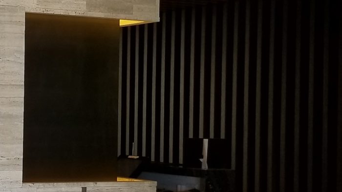 Kayu berwarna gelap menghiasi dinding di kounter meja resepsi