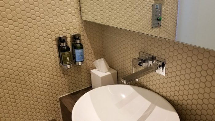 Dinding kamar mandi yang dilapisi dengan wallpaper berwarna krem