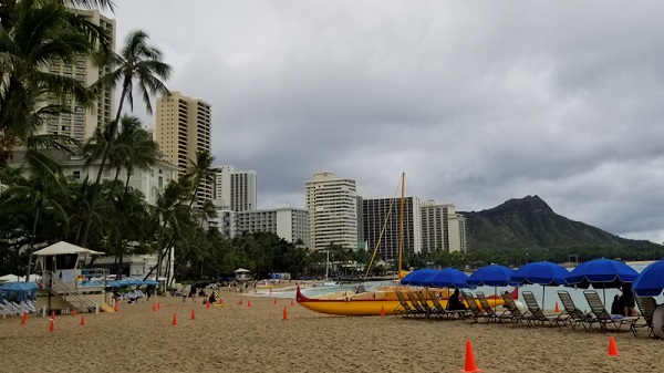 Canoe warna oranye dengan kontrasnya payung pantai biru