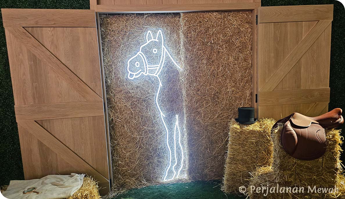 A glowing white neon outline of a horse on a straw wall, beside hay bales, saddle, top hat, and magnifying glass at the Hermès exit room