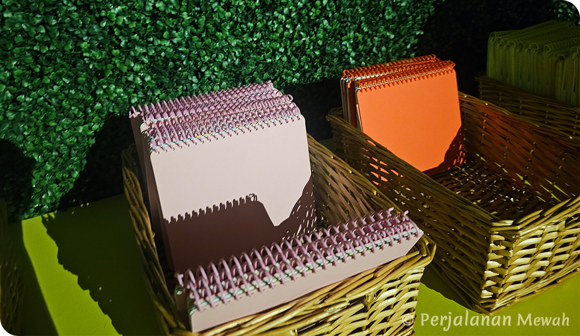 Hermès spiral-bound notebooks in signature colors arranged in wicker baskets as parting gifts